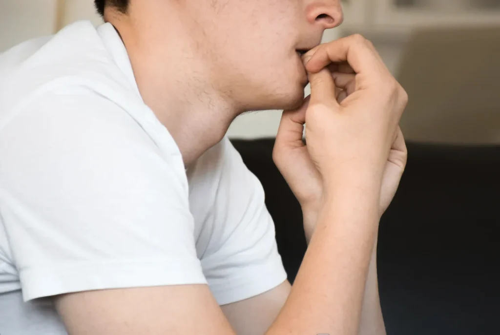 En bekymret mand bider negle og illustrerer den ængstelige profil.